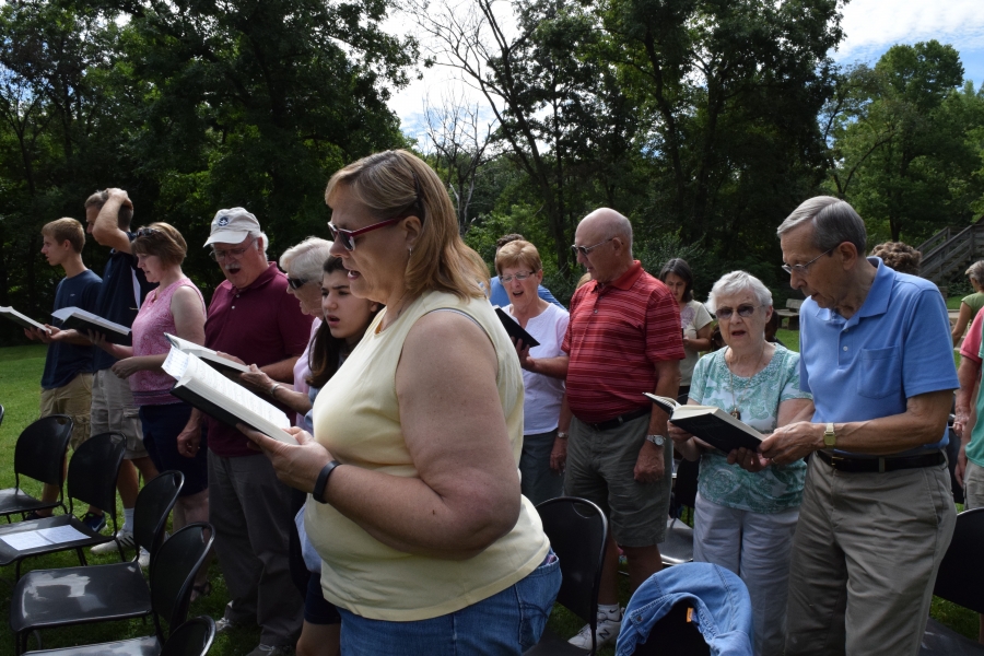 Crowd looks at hymn books and sings.
